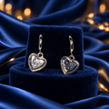Silver-Tone Glitter Heart Charm Hoop Earrings on decorative coloured satin background
