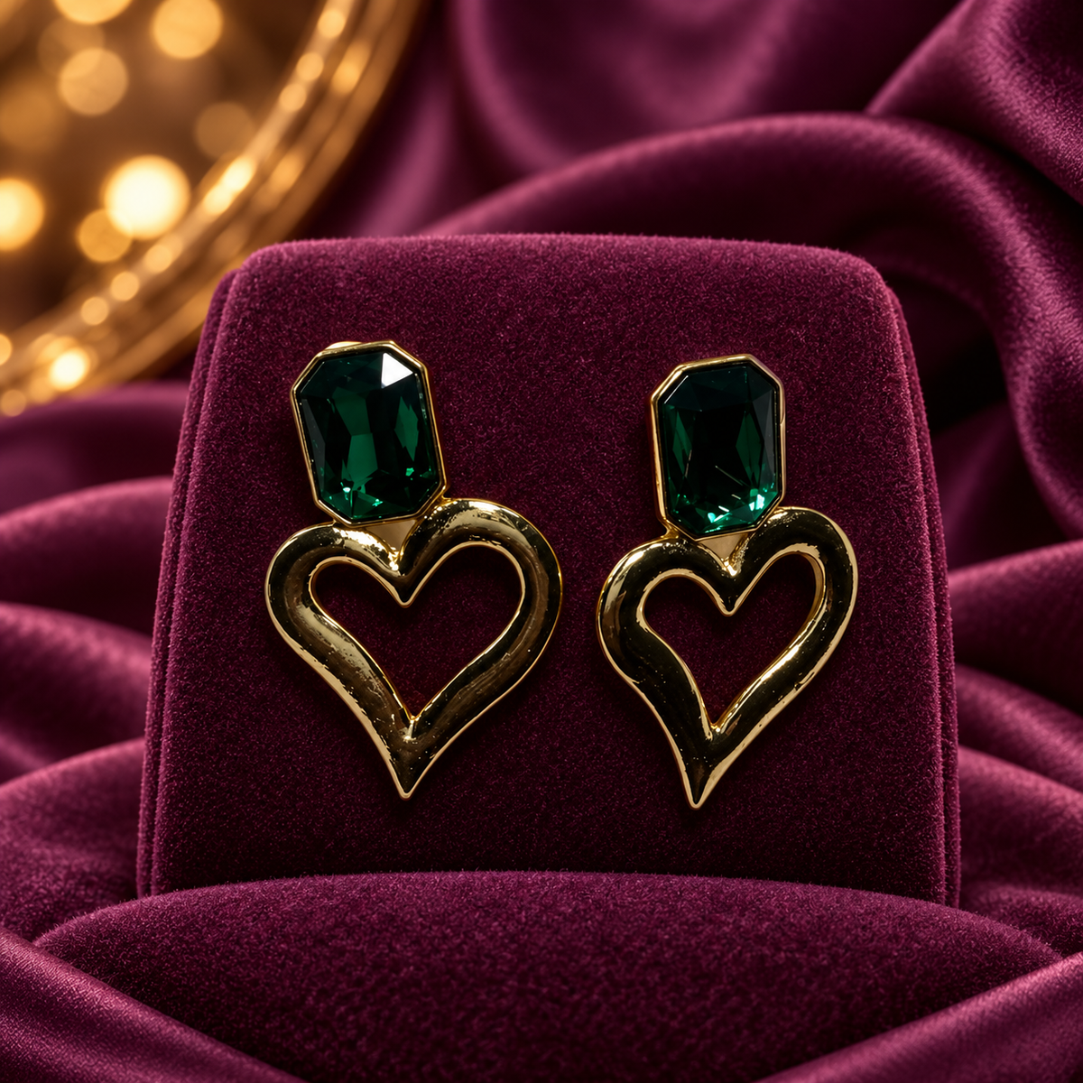 Gold-Tone Open Heart Drop Earrings with Dark Green Faceted Accents on plum velvet display
