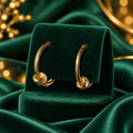 Gold-Tone Curved Knot Hoop Fashion Earrings on emerald velvet display